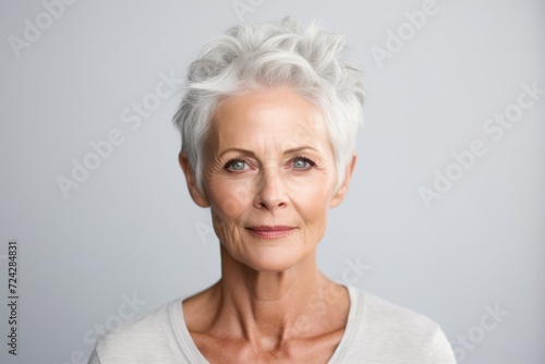 Portrait of beautiful senior woman with grey hair against grey background.