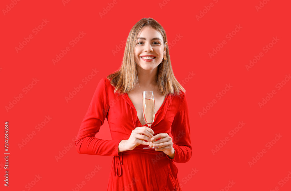 Beautiful happy young woman with glass of champagne on red background Beautiful happy young woman with glass of champagne on red background