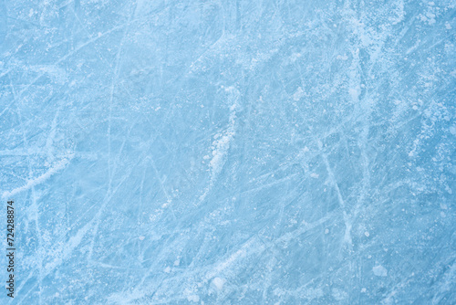 Icy background on rink with visible traces of skating, showcasing the essence of winter sport. Texture of ice on skating rink visible from top view, displaying sheet of scratched ice.