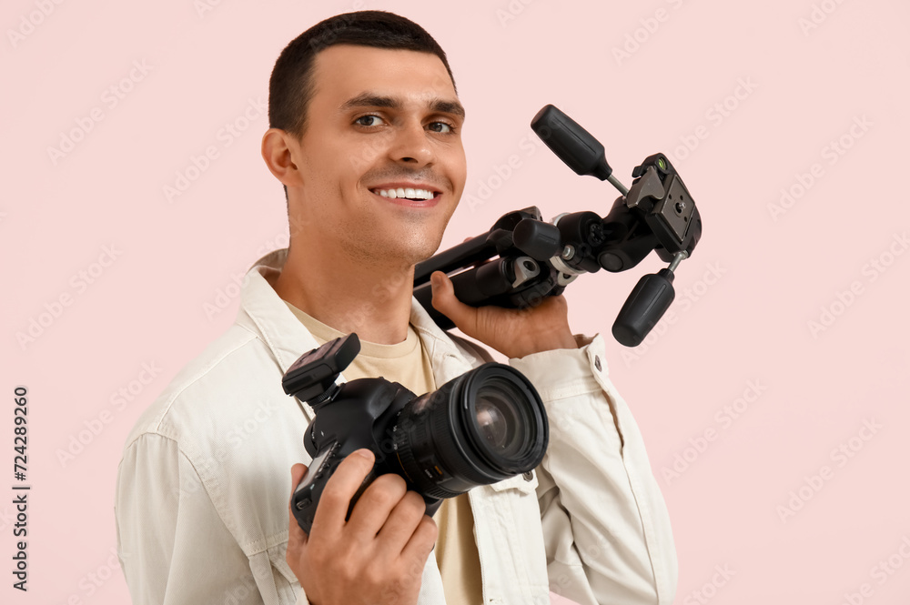 Male photographer with modern camera and tripod on pink background Male photographer with modern camera and tripod on pink background
