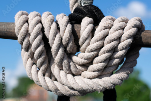 Thick, neatly looped rope hangs against a vivid blue sky, hinting at nautical adventures and precise maritime practices.