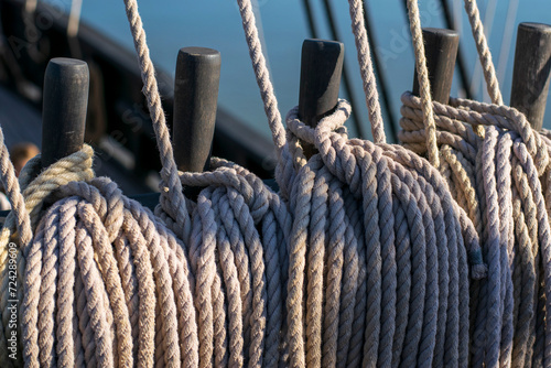 The early morning light gently illuminates the coiled ropes and wooden belaying pins of a classic sailing vessel, symbolizing age-old maritime traditions.