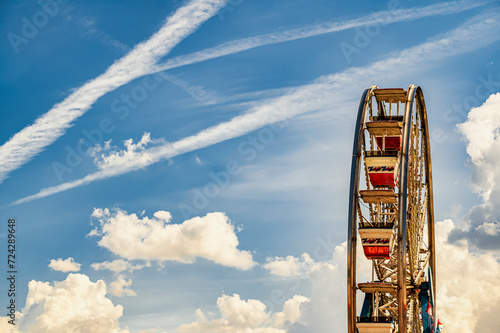 Vintage Ferris Wheel Against a Blue Sky With Contrails on a Sunny Day