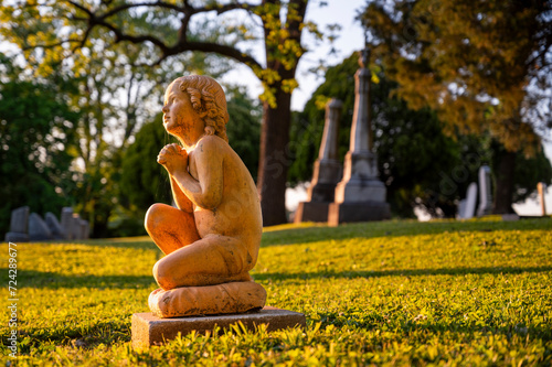 Serene Sunset Embrace Over a Cherubic Monument in a Tranquil Cemetery Setting
