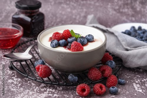 Bowl of tasty semolina porridge with fresh berries on grey background