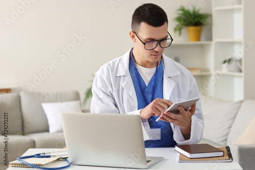 Young doctor video chatting with patient on laptop at home