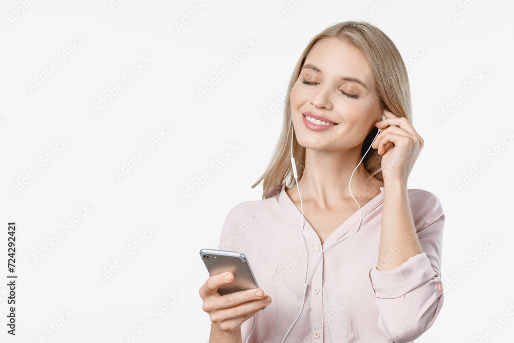Pleased caucasian woman in earphones enjoys listening to music while standing with eyes closed isolated over white background. Radio podcast e-learning song playlist e-book
