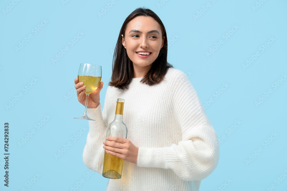 Beautiful young woman with bottle and glass of white wine on blue background Beautiful young woman with bottle and glass of white wine on blue background
