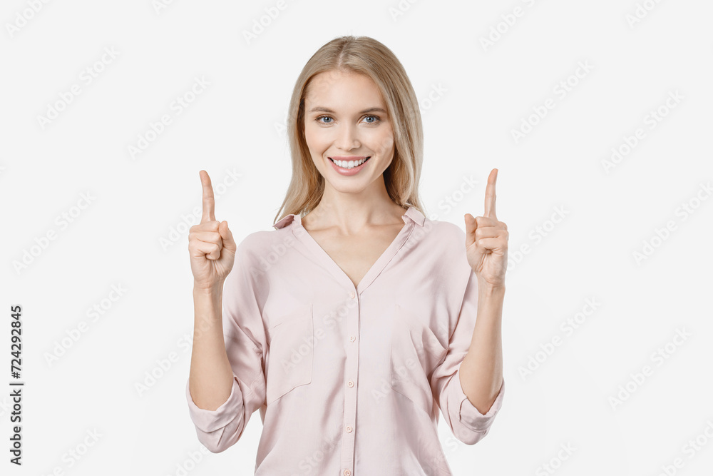 Happy young woman standing and pointing finger on copy space isolated over white background. Female influencer showing free empty space for advertisement Happy young woman standing and pointing finger on copy space isolated over white background. Female influencer showing free empty space for advertisement