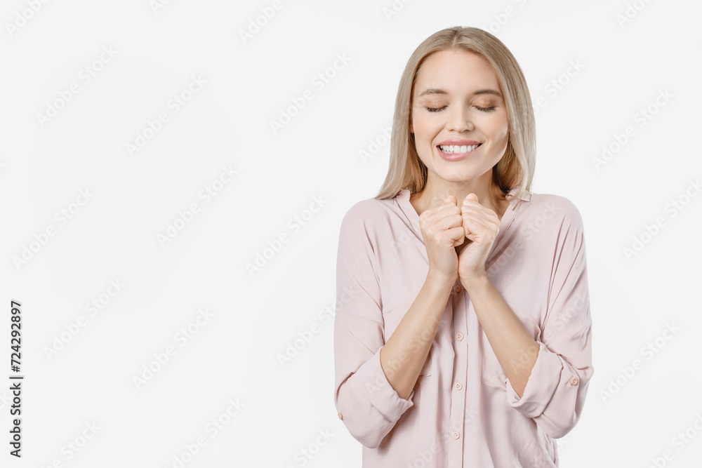 Young smiling girl with closed eyes keeps palms together makes a wish. Caucasian female dreaming having a desire isolated over white background Young smiling girl with closed eyes keeps palms together makes a wish. Caucasian female dreaming having a desire isolated over white background