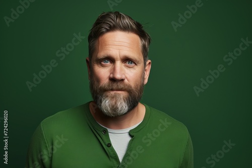 Portrait of a handsome man with long beard and mustache. Studio shot against green background.