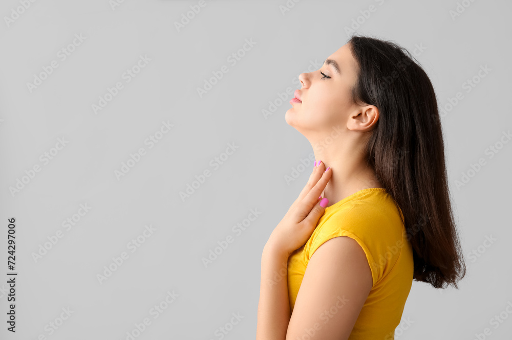 Young woman with thyroid gland problem on grey background Young woman with thyroid gland problem on grey background