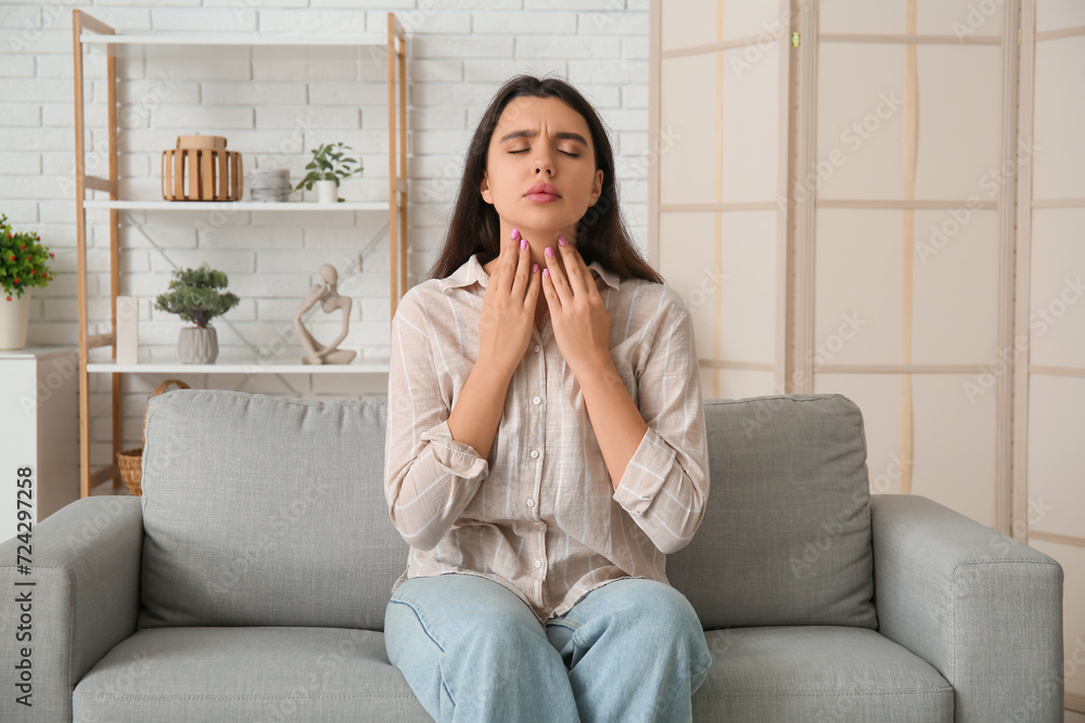 Young woman with thyroid gland problem sitting on sofa at home Young woman with thyroid gland problem sitting on sofa at home
