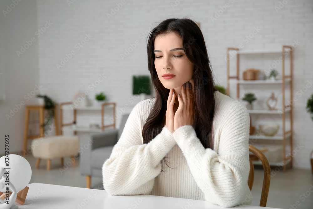 Young woman with thyroid gland problem sitting at table in living room Young woman with thyroid gland problem sitting at table in living room