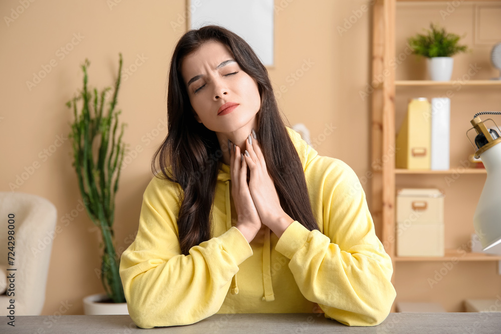 Young woman with thyroid gland problem sitting at table in living room Young woman with thyroid gland problem sitting at table in living room