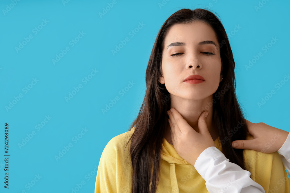 Endocrinologist examining thyroid gland of young woman on blue background Endocrinologist examining thyroid gland of young woman on blue background
