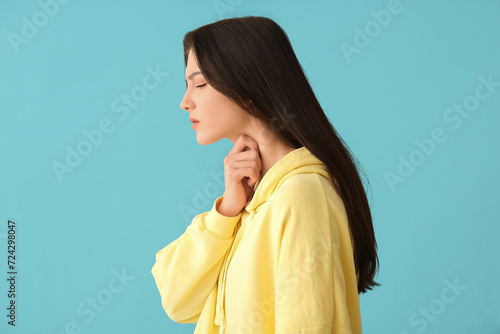 Young woman with thyroid gland problem on blue background photo
