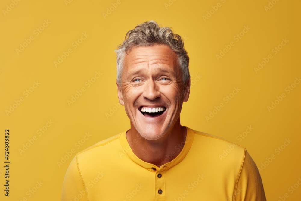 Portrait of a cheerful mature man laughing against yellow studio background. Portrait of a cheerful mature man laughing against yellow studio background.