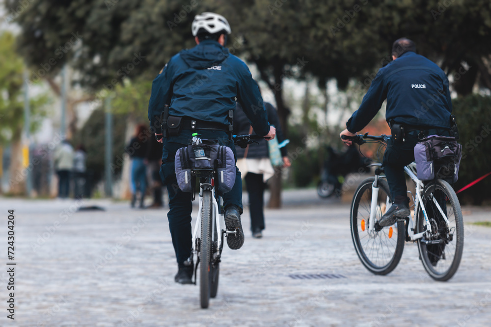 Fototapeta premium Police squad formation on duty riding bike and bicycle, maintain public order in the european city streets, group of policemen patrol on bycicles with 
