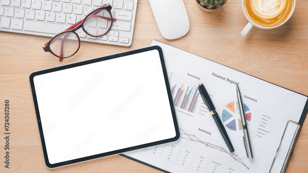 A neatly organized workspace featuring a blank tablet screen, keyboard, glasses, and a detailed finance report, perfect for business analysis and planning. A neatly organized workspace featuring a blank tablet screen, keyboard, glasses, and a detailed finance report, perfect for business analysis and planning.