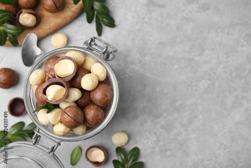 Tasty Macadamia nuts in jar on light grey table, flat lay. Space for text photo