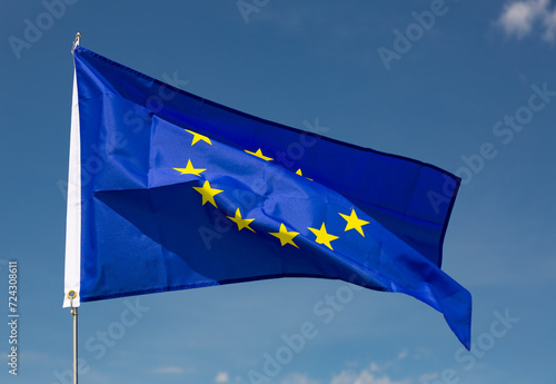 On clear sunny day,flag of European Union flies on flagpole against blue sky