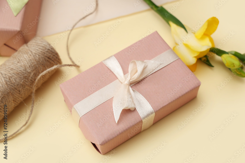 Gift box with beautiful flower and string on yellow background. International Women's Day Gift box with beautiful flower and string on yellow background. International Women's Day