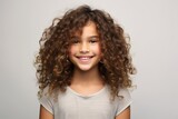 Portrait of a smiling little girl with curly hair over grey background