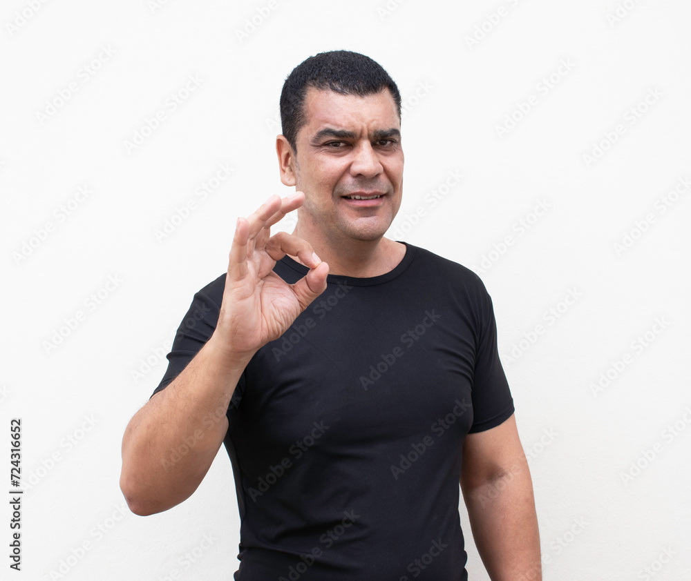 Portrait of a cheerful man showing okay gesture isolated on white wall background Portrait of a cheerful man showing okay gesture isolated on white wall background