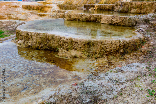 Unique rust coloured travertine terraces with mineral hot water of Karahyit Red Springs, Denizli Province, Turkey photo