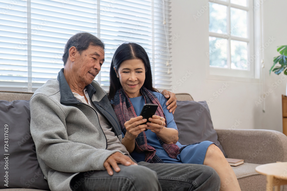 Portrait of Asian adorable senior couple using smartphone together video chatting with family in living room at home. Portrait of Asian adorable senior couple using smartphone together video chatting with family in living room at home.