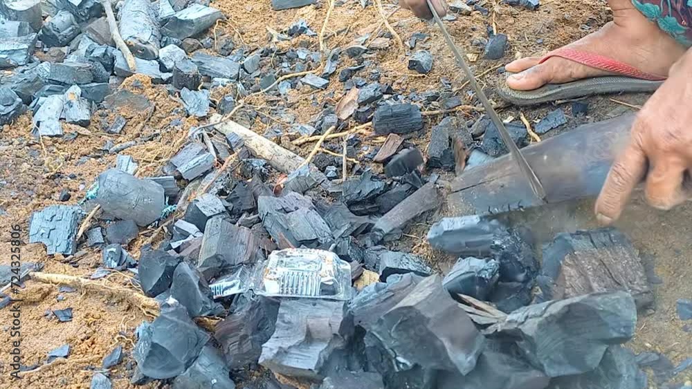 A Worker Is Cutting Pieces Of Charcoal Wood On The Garden Ground During The Day