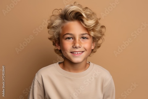 Portrait of a smiling little boy with curly hair on a brown background