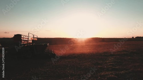 a tractor pulling a planter at sunset