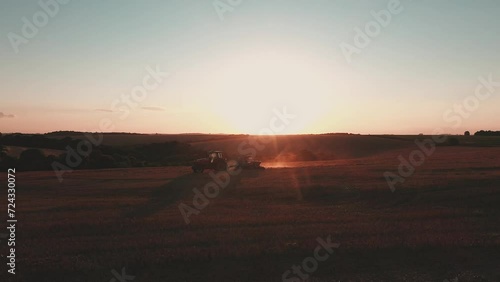 a tractor pulling a planter at sunset