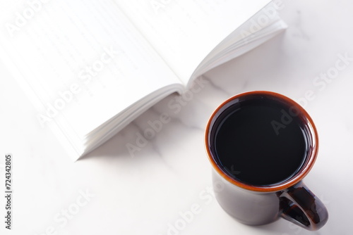 テーブルの上の開いた本とコーヒーカップで、コーヒーを飲みながら読書を楽しむイメージ