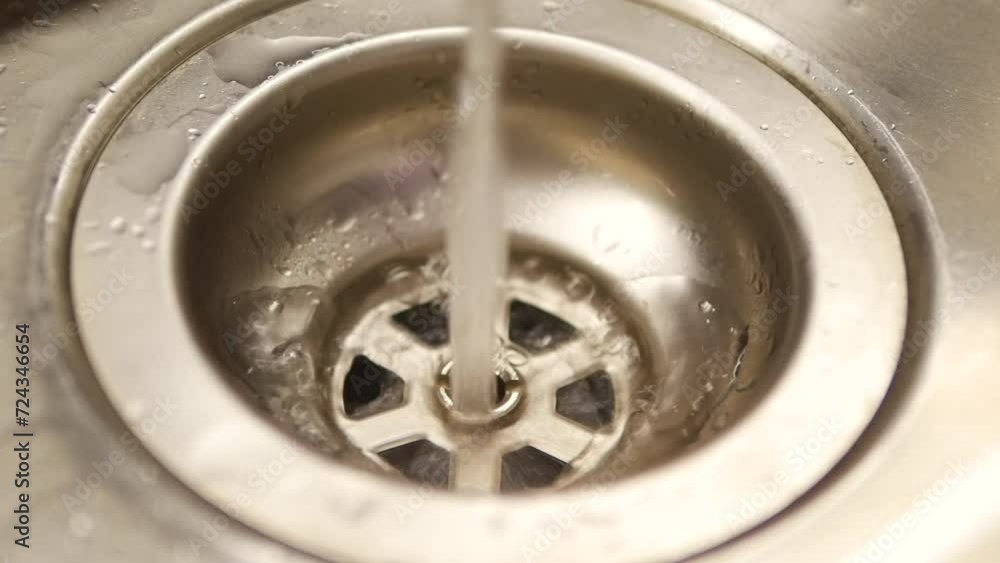 Leaking faucet leaves droplets of water in big silver sink. Water flowing from loosely closed faucet and lasting small drops in sink in kitchen Leaking faucet leaves droplets of water in big silver sink. Water flowing from loosely closed faucet and lasting small drops in sink in kitchen
