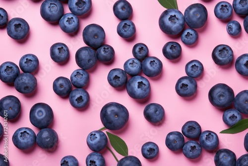 Blueberries are scattered across a vibrant pink surface, creating a visually striking contrast. © pham