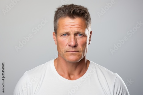 Portrait of handsome middle aged man looking at camera over grey background © Iigo