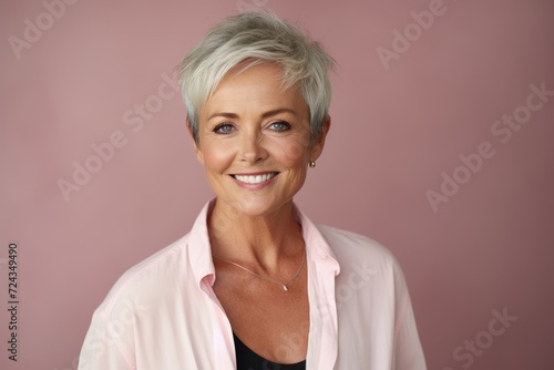 Beautiful middle aged woman smiling at camera. Isolated on a pink background.