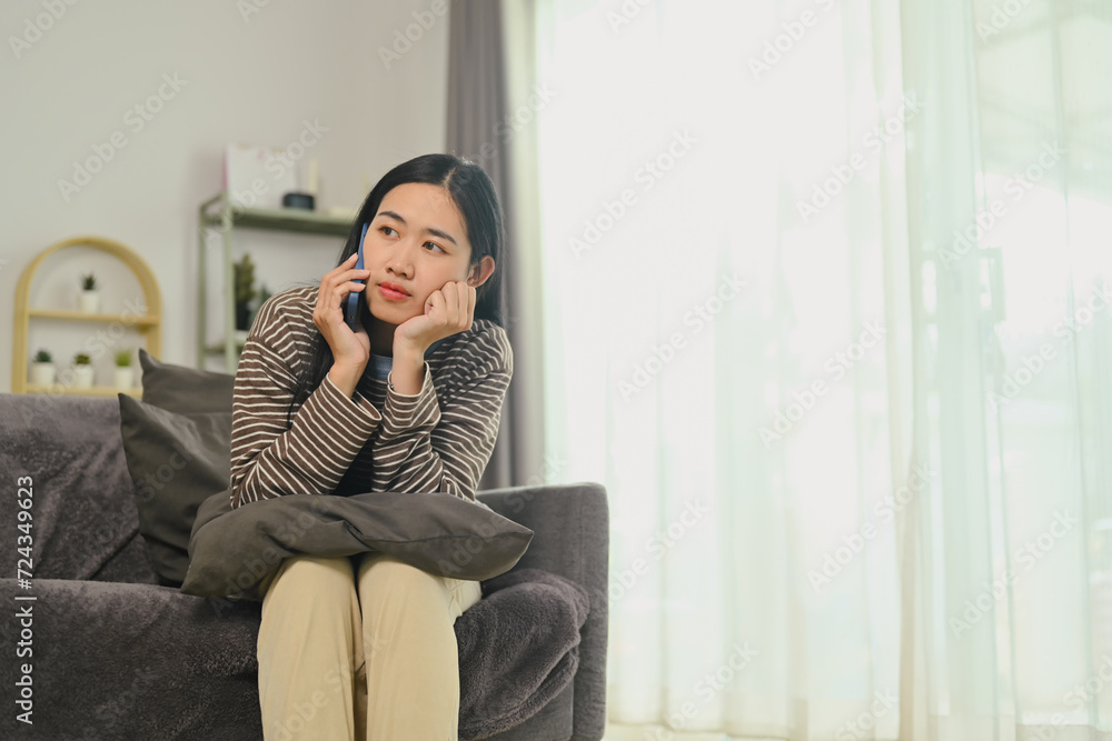 Thoughtful young woman talking on mobile phone and looking away, thinking of problem solution, considering idea Thoughtful young woman talking on mobile phone and looking away, thinking of problem solution, considering idea