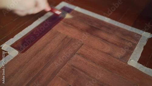 Painting wood stain on wooden floor with brush photo