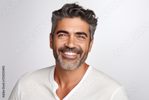 Handsome middle-aged man smiling and looking at camera while standing against grey background