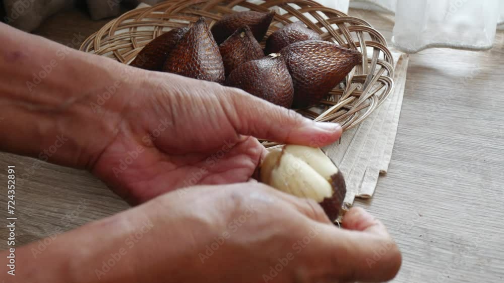 a man peels salak fruit or snake fruit (salacca zalacca), indonesian native fruit. a man peels salak fruit or snake fruit (salacca zalacca), indonesian native fruit.