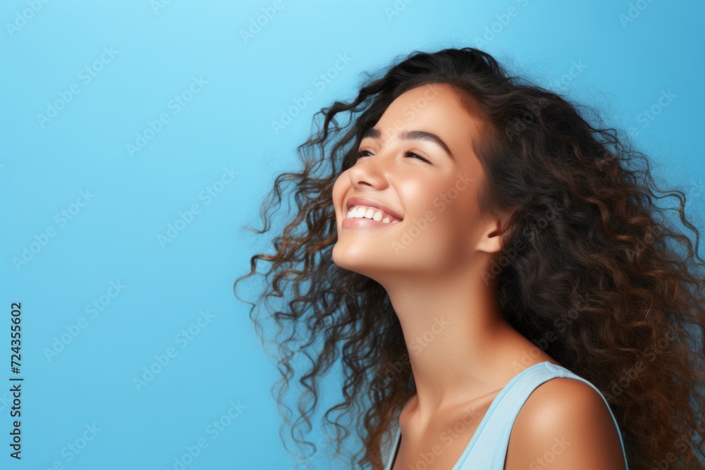 Portrait of a beautiful young woman with long curly hair on blue background