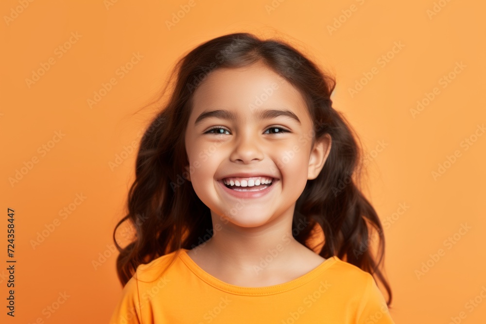 Portrait of cheerful little girl looking at camera and smiling, over orange background Portrait of cheerful little girl looking at camera and smiling, over orange background