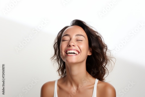 Portrait of beautiful young woman laughing with closed eyes on white background