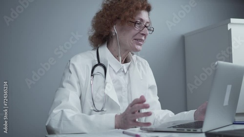 Telemedicine services. Primary care consultations, psychotherapy, emergency services. Female doctor talking and gesturing while having online consultation on laptop. Medicine, healthcare concept. photo