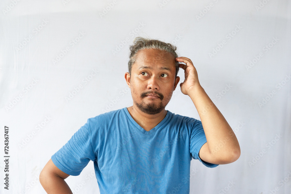 Thoughtful Asian curly male on white background contemplates about something, thinking an idea Thoughtful Asian curly male on white background contemplates about something, thinking an idea