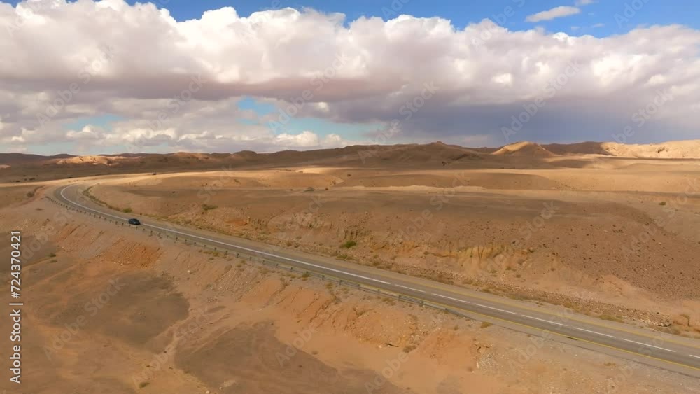 Car zooming by heading north on a Desert highway with cloudy blue sky Car zooming by heading north on a Desert highway with cloudy blue sky